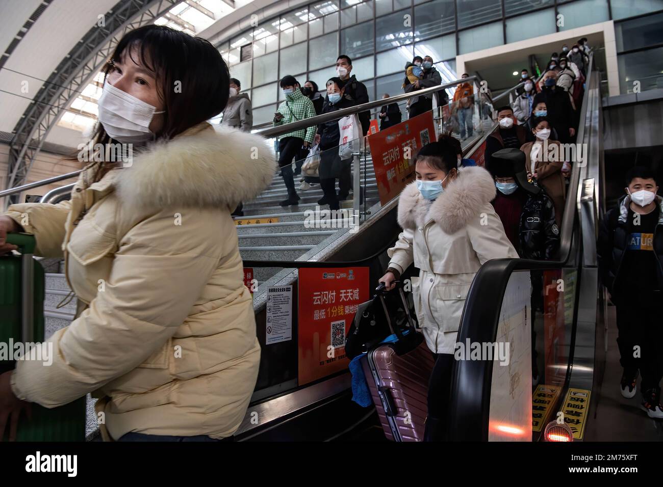 Passagiere mit Gesichtsmasken fahren am ersten Tag des chinesischen Frühlingsfestivals in Wuhan auf einer Rolltreppe zum Bahnhof Hankow. Am Samstag, dem ersten Tag des diesjährigen Frühjahrsfestes, werden voraussichtlich rund 6,3 Millionen Fahrten durch China unternommen, so der nationale Eisenbahnbetreiber China State Railway Group. China hat kürzlich sein epidemisches Kontrollmanagement optimiert, und auch epidemische Maßnahmen für Reisen wurden letzten Monat optimiert. Reisende benötigen keine negativen Nukleinsäuretests oder Gesundheitscodes mehr, müssen sich nicht mehr nuc unterziehen Stockfoto