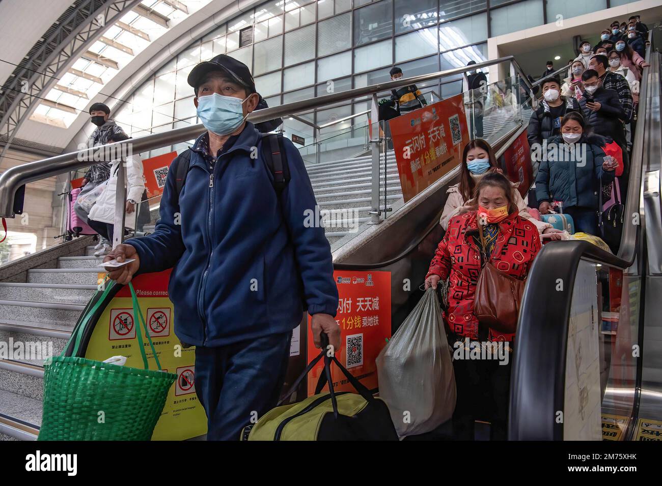 Passagiere mit Gesichtsmasken fahren am ersten Tag des chinesischen Frühlingsfestivals in Wuhan auf einer Rolltreppe zum Bahnhof Hankow. Am Samstag, dem ersten Tag des diesjährigen Frühjahrsfestes, werden voraussichtlich rund 6,3 Millionen Fahrten durch China unternommen, so der nationale Eisenbahnbetreiber China State Railway Group. China hat kürzlich sein epidemisches Kontrollmanagement optimiert, und auch epidemische Maßnahmen für Reisen wurden letzten Monat optimiert. Reisende benötigen keine negativen Nukleinsäuretests oder Gesundheitscodes mehr, müssen sich nicht mehr nuc unterziehen Stockfoto