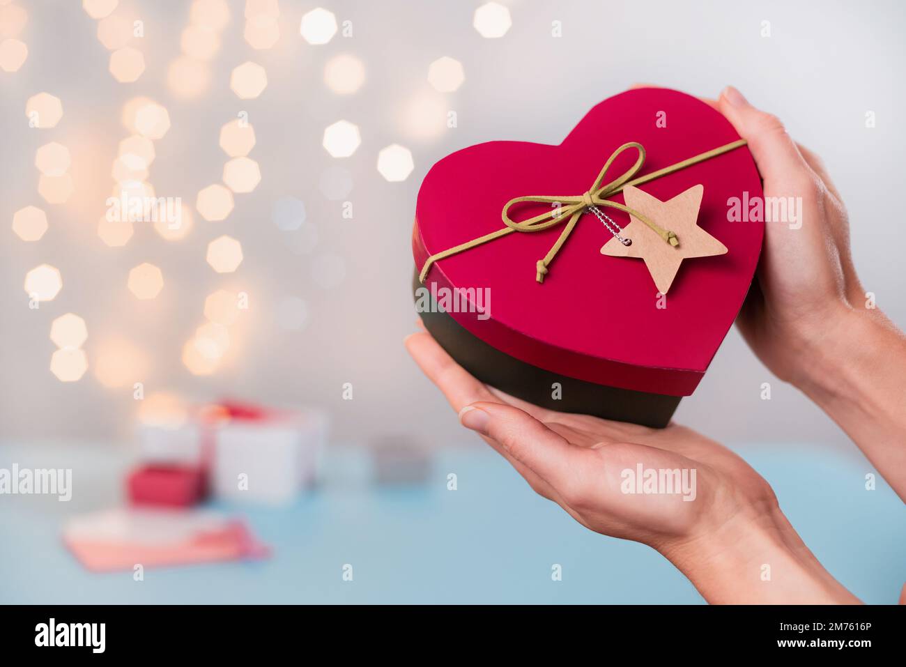 St. Valentinstagsgeschenke in herzförmiger Box in den Händen. Kopierbereich für Liebesbotschaft. Wählen Sie ein Neujahrsgeschenk für geliebte Person, Nahaufnahme, Bokeh Stockfoto