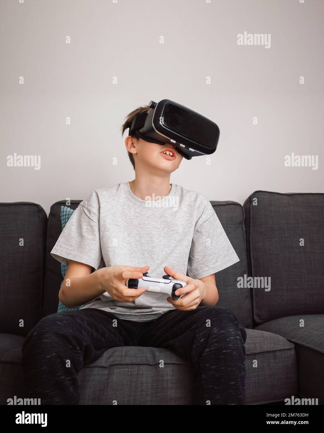 Junge, der Spaß beim Spielen von Simulationsspielen hat, mit Virtual-Reality-Headset und Controller. Kinder und modernes Technologiekonzept. Stockfoto