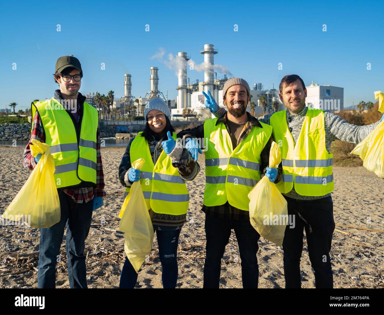 Eine Gruppe von multiethnischen jungen Freiwilligen, die Müll in der Natur sammeln und sich ein Lächeln in der Kamera ansehen. Ökologengruppe, Earth-Day-Konzept Stockfoto