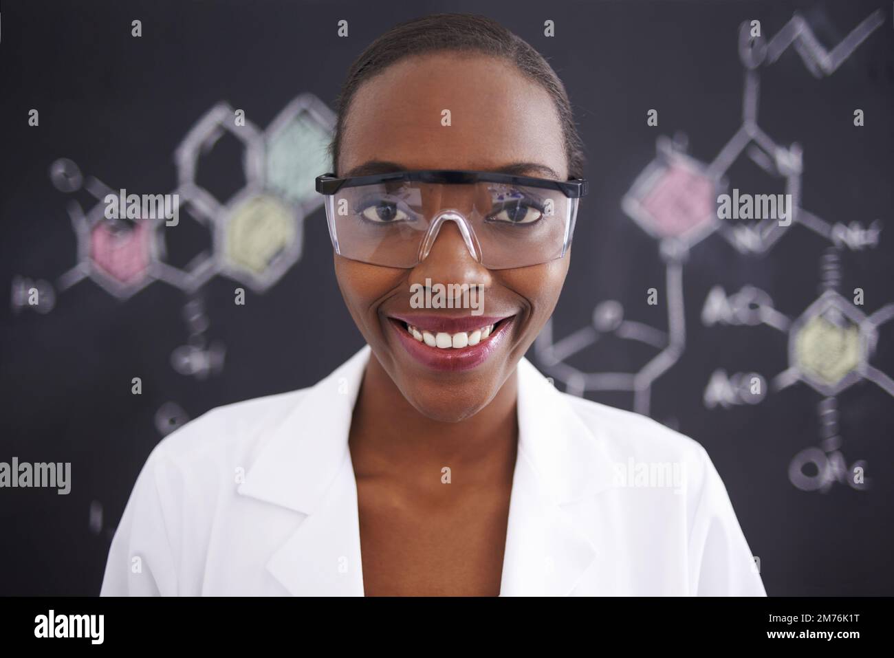 Sie ist verrückt nach Molekülen. Eine Wissenschaftlerin steht vor einer Tafel voller Zeichnungen chemischer Bindungen. Stockfoto