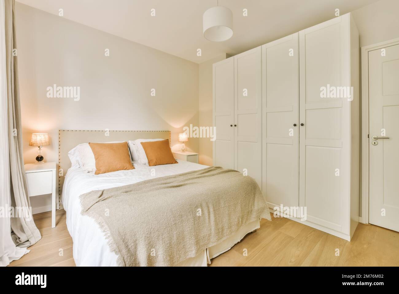 Ein Schlafzimmer mit einem Bett und Schränken in der Ecke, von der Seite genommen, um zu zeigen, wie es gemacht wird Stockfoto