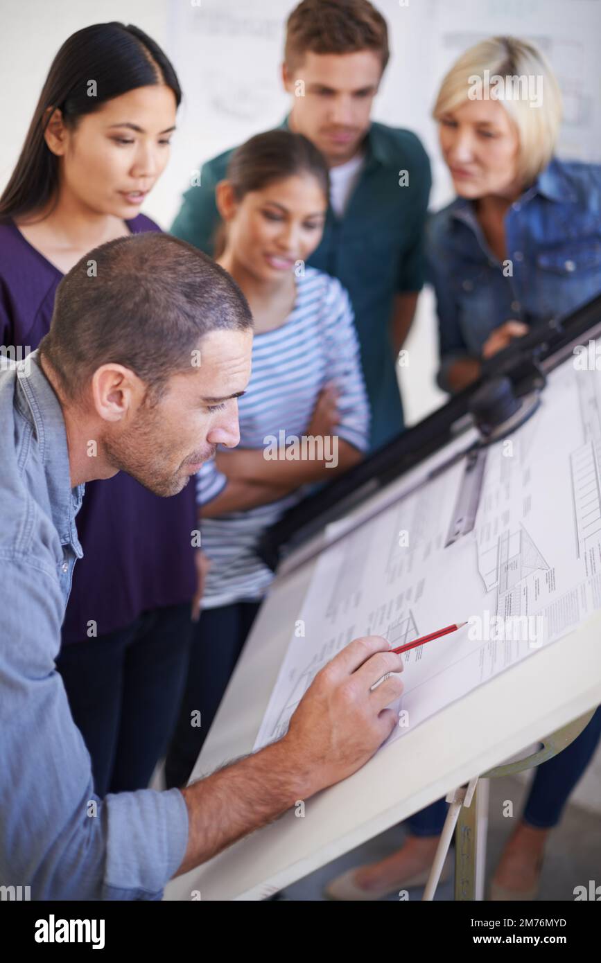 Sie waren alle von seiner Arbeit beeindruckt. Eine Gruppe von Architekten, die Pläne diskutieren. Stockfoto