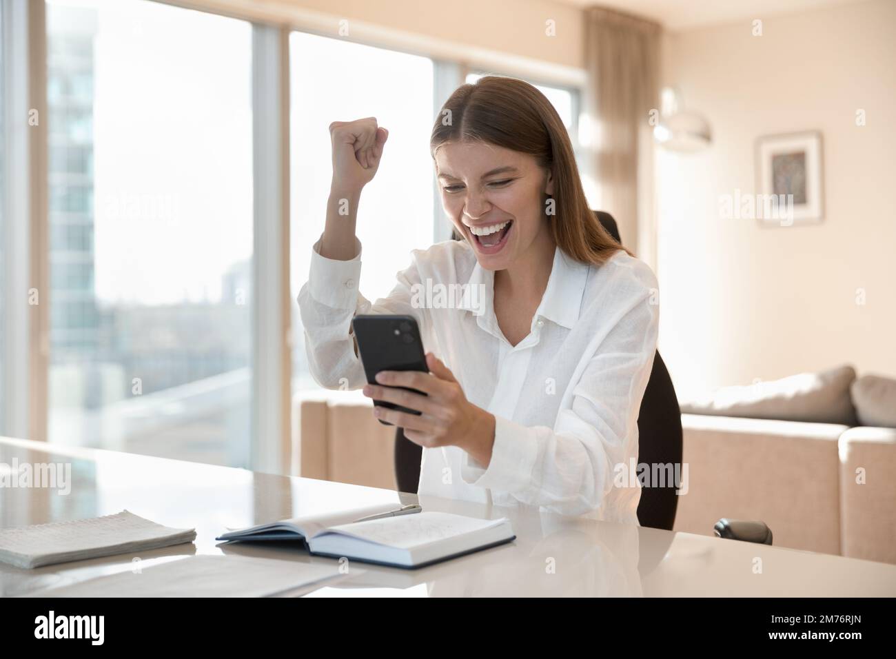Eine Frau hält das Telefon und erhalte fantastische Nachrichten per sms. Fühlt sich glücklich an Stockfoto