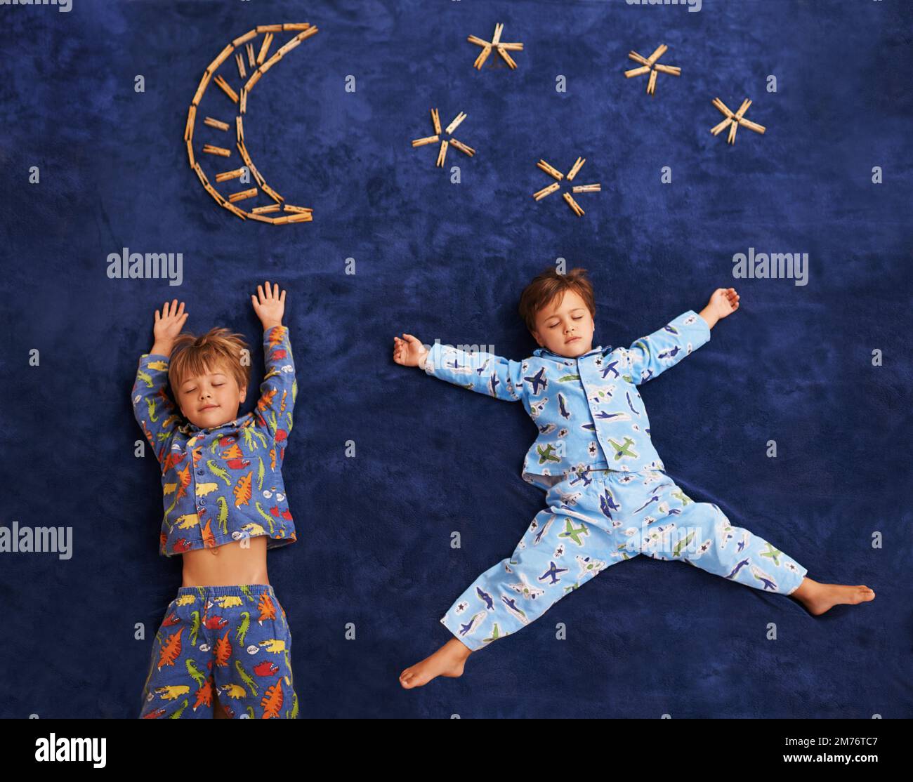 Nicht bewegen, sie kommt. Zwei kleine Jungs liegen mit geschlossenen Augen auf einem Teppich. Stockfoto