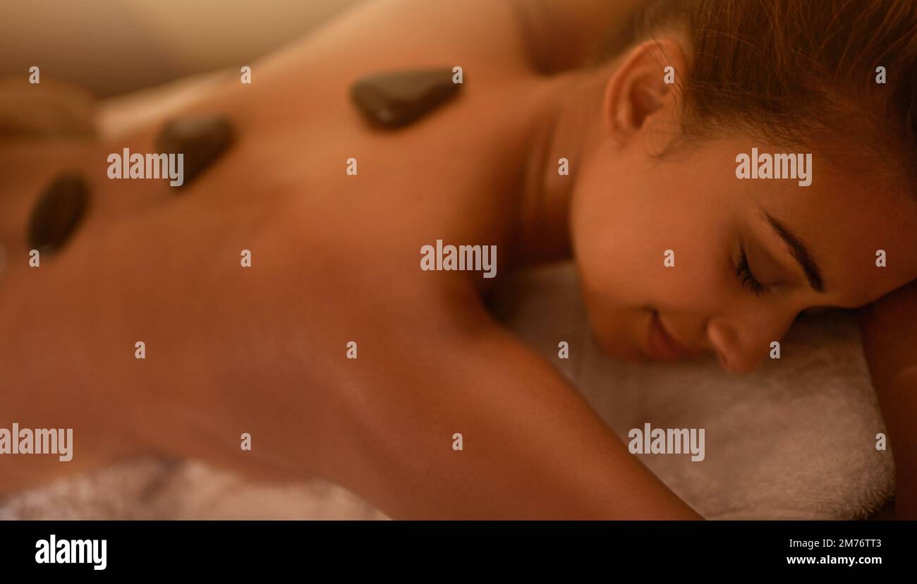 Entspannung ist das A und O. Eine junge Frau, die eine Hot-Stone-Therapie in einem Spa genießt. Stockfoto