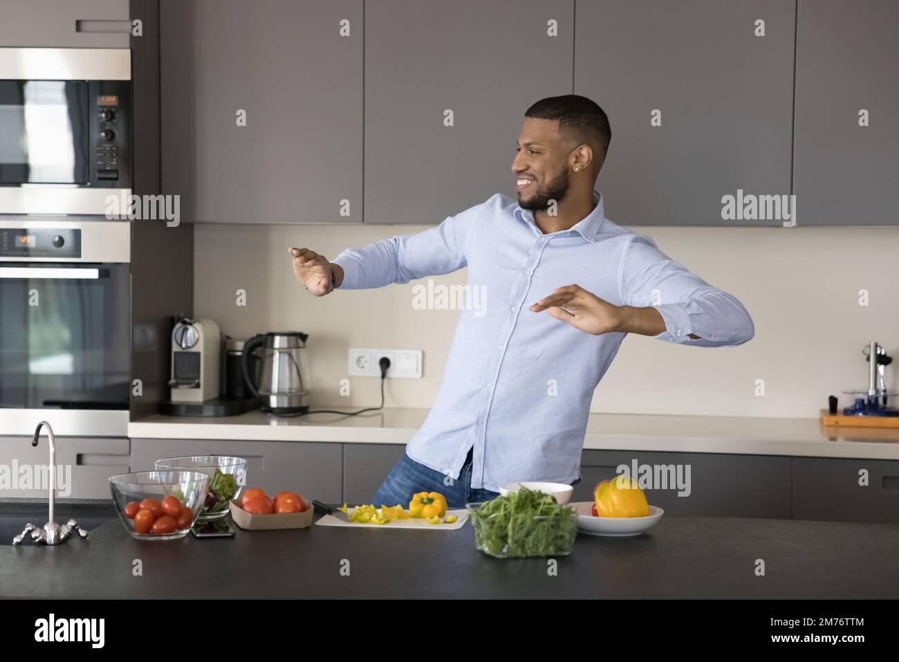 Sorgenfreier, lebendiger afrikanischer Single-Mann, der in der modernen Küche tanzt Stockfoto