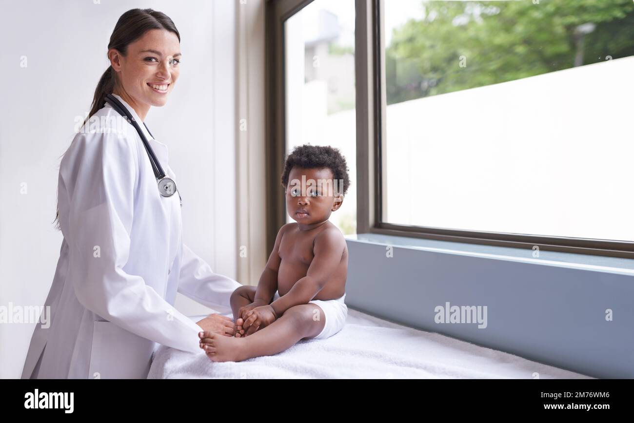 Gerade in für eine routinemäßige pädiatrische Untersuchung. Eine weibliche Kinderärztin, die eine Untersuchung an einem entzückenden kleinen Jungen macht. Stockfoto