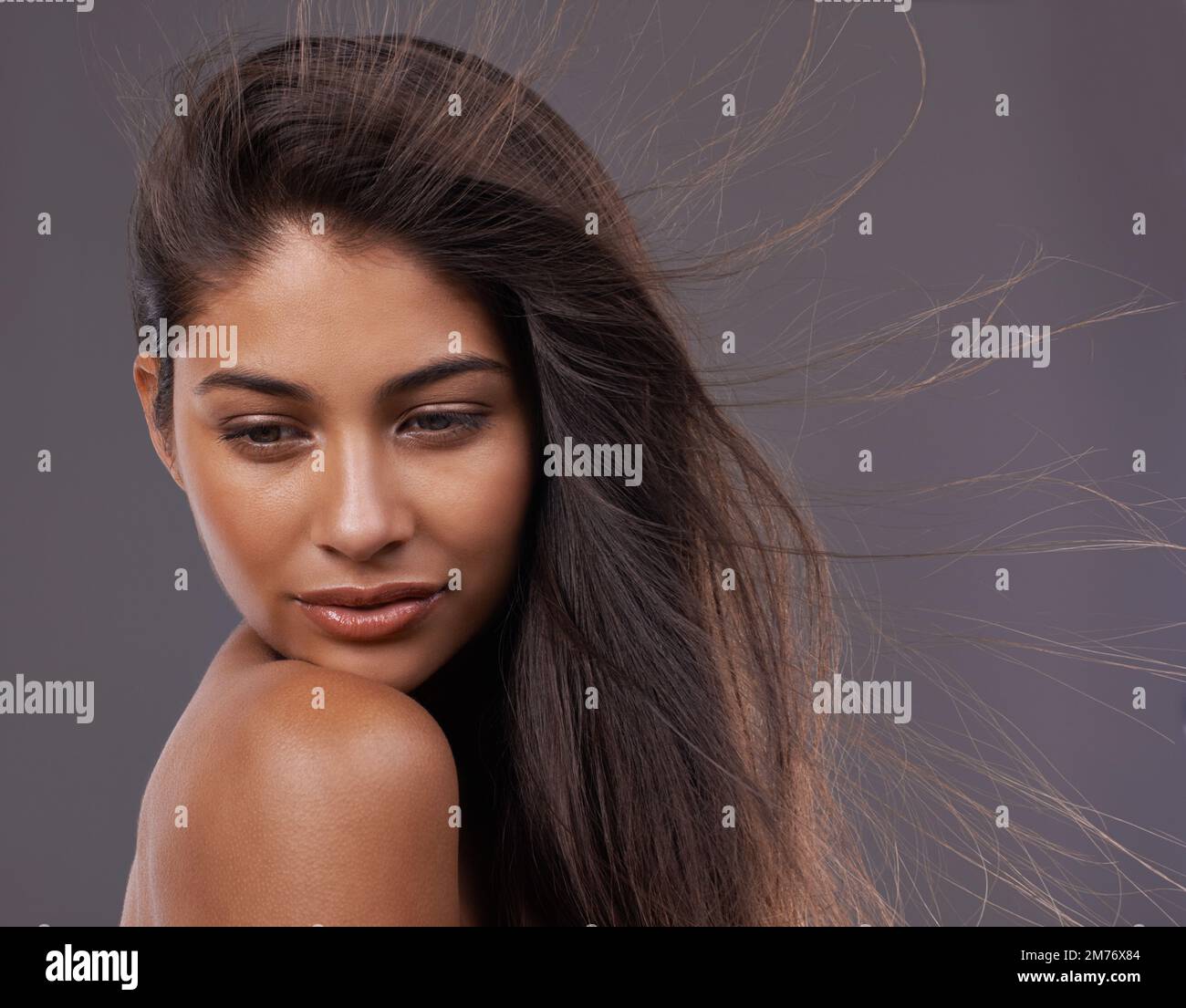 Wahre Schönheit - frei und unkompliziert. Eine attraktive junge Frau mit windgepeitschtem Haar im Studio. Stockfoto