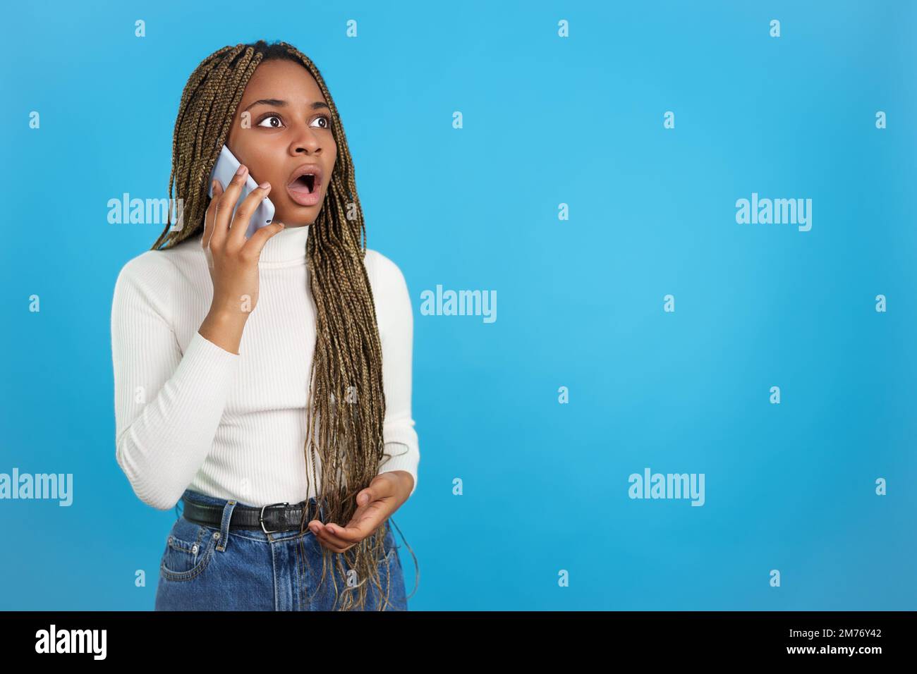 Afrikanische Frau mit einem überraschenden Gesichtsausdruck, die mit dem Handy spricht Stockfoto