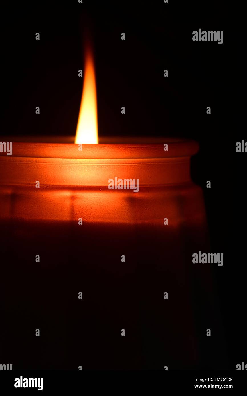 Nahaufnahme eines Kerzenlichts auf dunklem Hintergrund. Symbol der Liebe, des Glaubens und der Erinnerung. Stockfoto