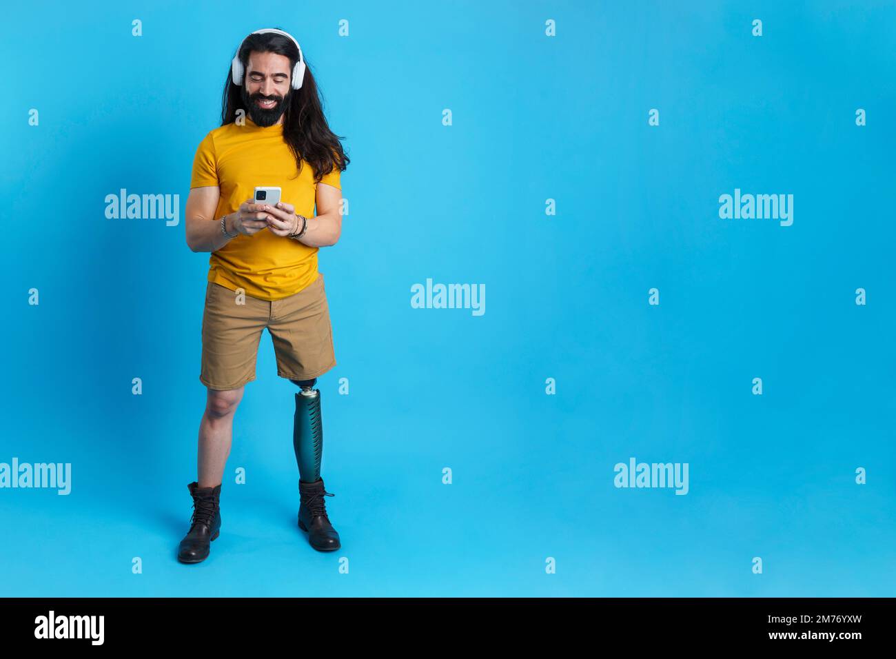 Mann mit Beinprothese, der Musik mit dem Mobile hört Stockfoto