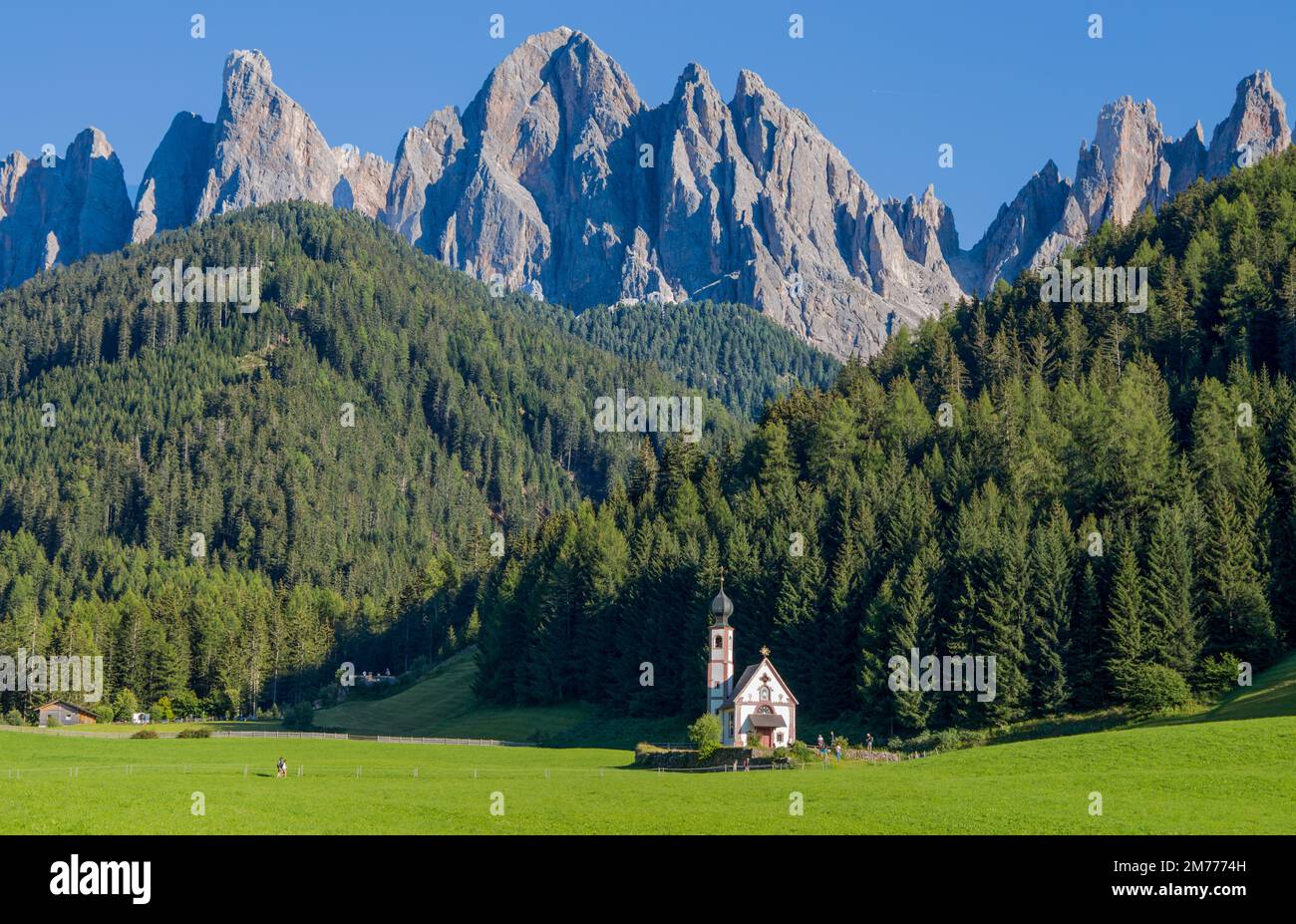 Blick auf die San Giovanni (St. John) Kirche in Ranui in Funes mit der Odle-Gebirgsgruppe im Hintergrund, Südtirol, Italien Stockfoto