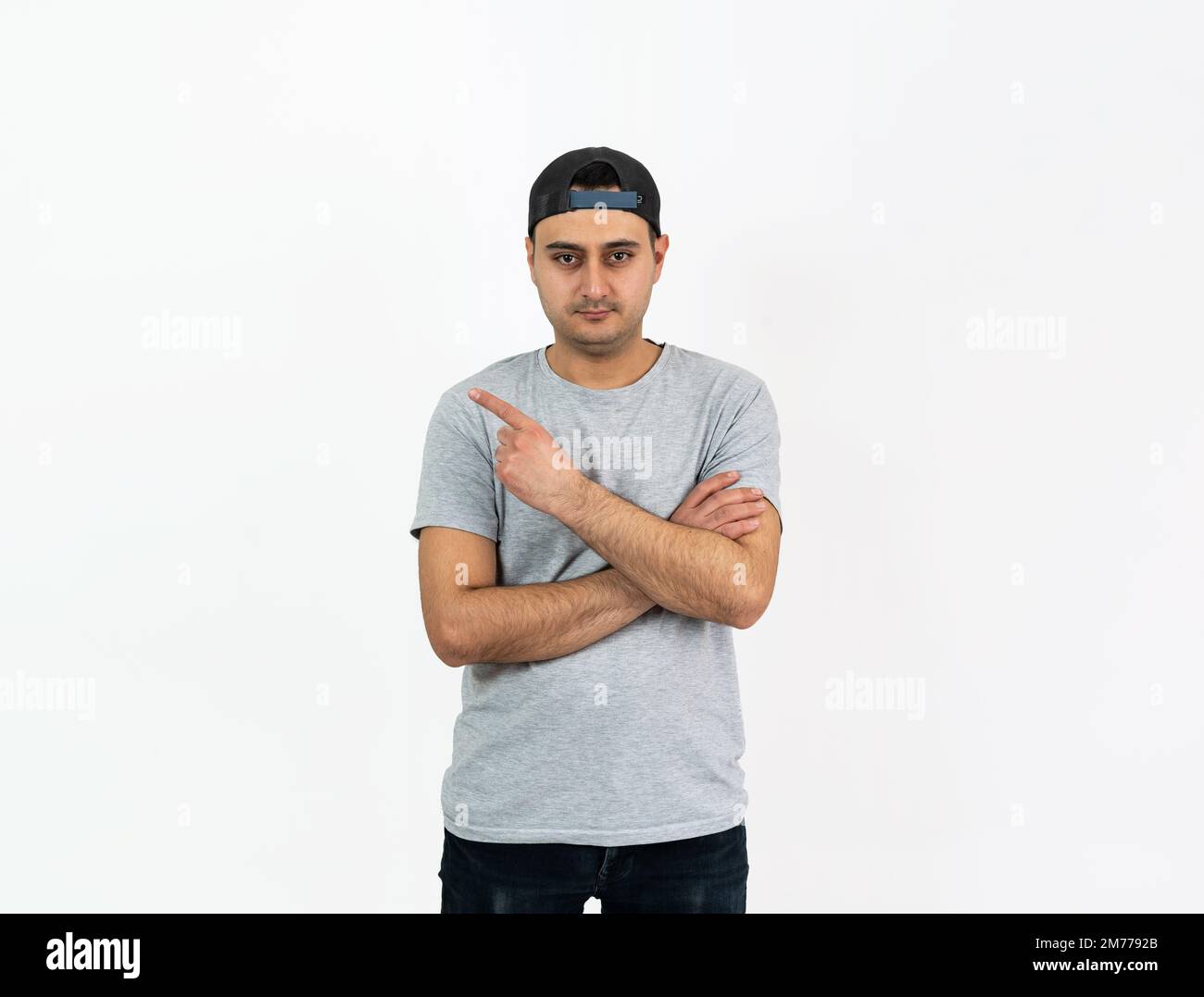 Nahaufnahme des Studiofotos eines jungen erwachsenen, braungehäuteten Mannes, der mit dem Finger auf einen Kopierbereich oder einen Textbereich zeigt. Stockfoto