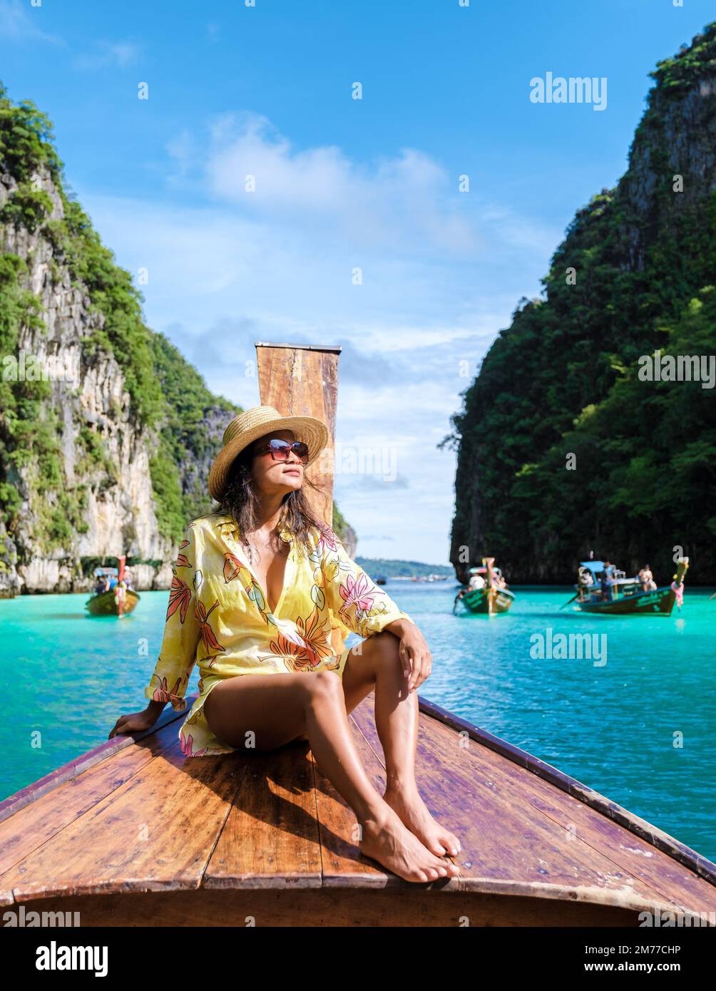 Asiatische Frauen vor einem Langboot in Kho Phi Phi Thailand, Frauen vor einem Boot in der Pileh Lagune Stockfoto