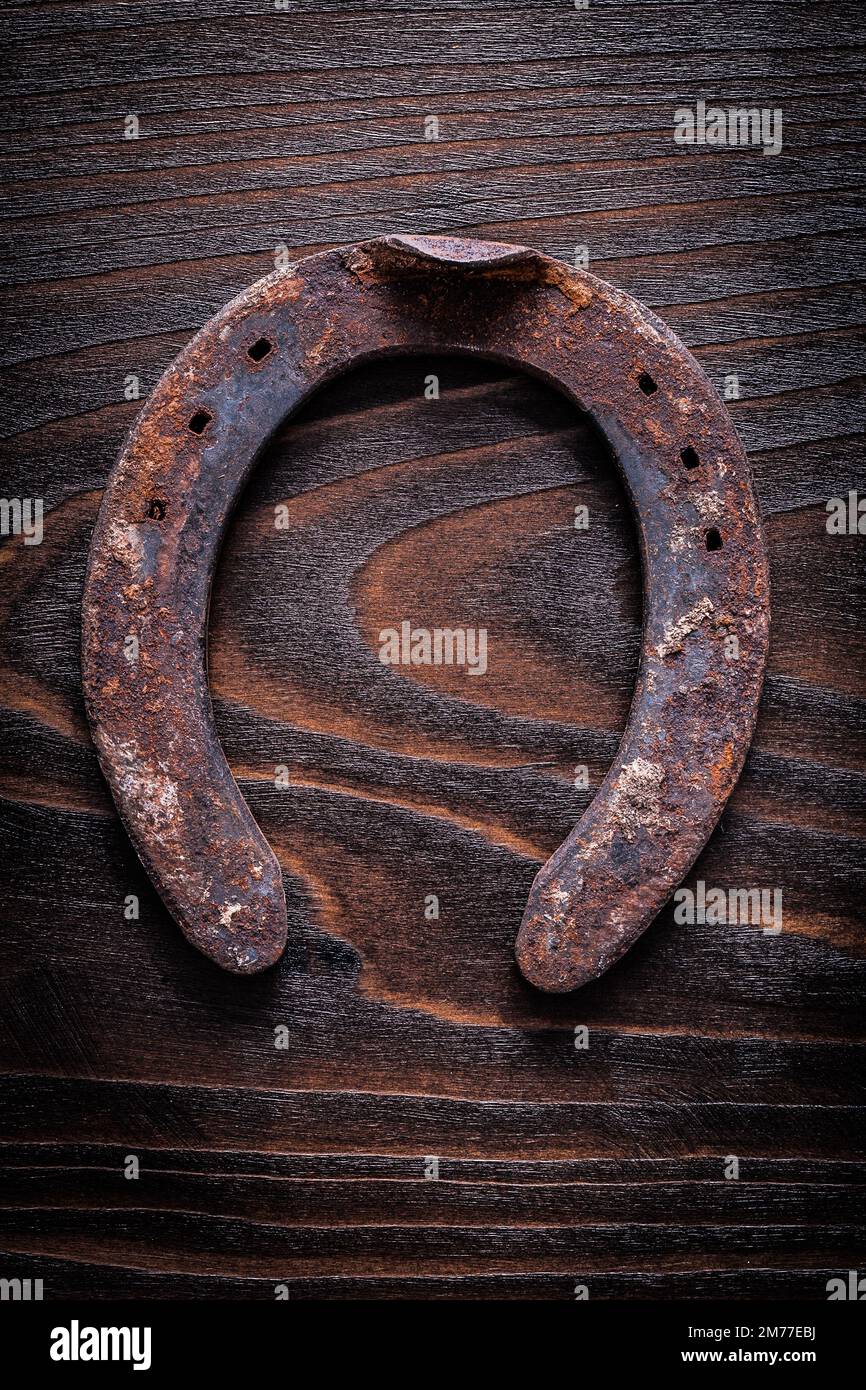 Rostiges, langjähriges Horsehoe auf altem dunklem Holzbrettbaukonzept. Stockfoto