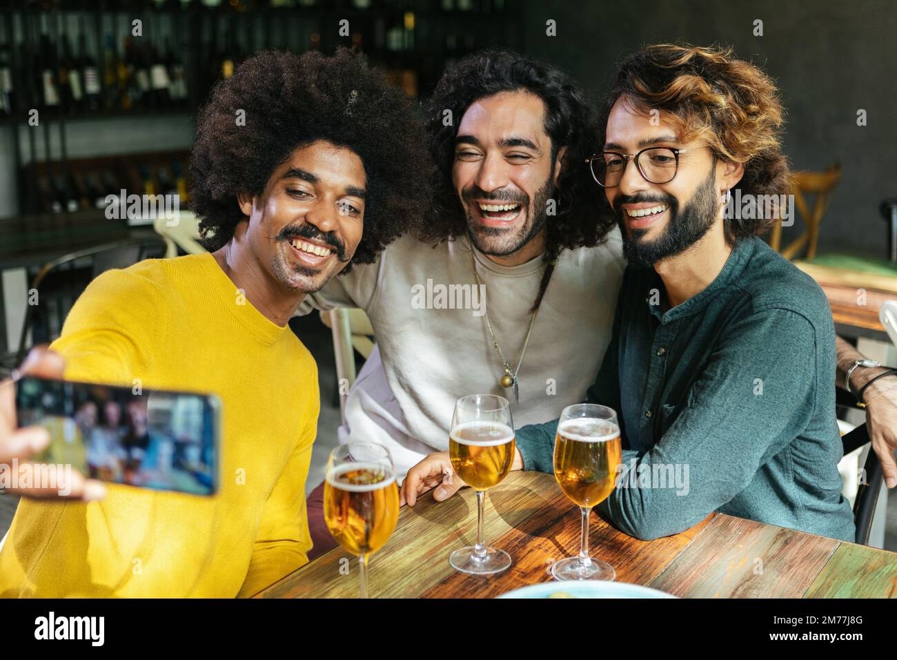 Junge multiethnische Freunde machen Selfie mit Telefon am Tisch in der Restaurantbar Stockfoto