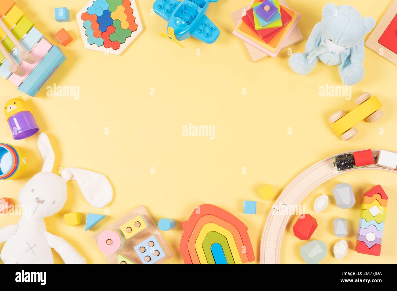 Hintergrund für Spielzeugrahmen für Babys und Kinder. Holz, Kunststoff, pädagogisch, musikalisch, sensorisch, Sortieren und Stapeln von Kinderspielzeug auf gelbem Hintergrund. Draufsicht Stockfoto