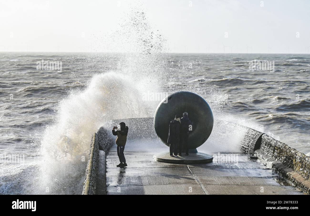 Brighton UK 8. Januar 2023 - Besucher werden nass, wenn sie beobachten, wie die Wellen am Brighton Beach und am Meer an der berühmten Donut-Skulptur einschlagen, während Stürme die Südküste heute mit einer Mischung aus starkem Wind, Sonnenschein und Regen treffen : Credit Simon Dack / Alamy Live News Stockfoto
