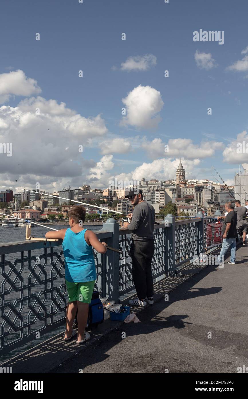Blick auf die Fischer auf der Galata-Brücke in Istanbul. Der Galata-Turm und das Viertel Beyoglu sind im Hintergrund. Das Bild spiegelt den Lebensstil und die lokale Kultur wider Stockfoto