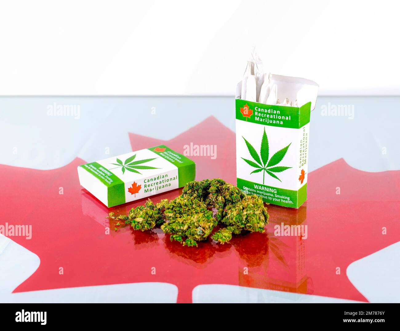 Cannabis in Kanada. Zwei Packungen Marihuana-Zigaretten mit Knospen, die auf einem Glastisch lagen. Ein Ahornblatt ist unter dem Glas. Die Gelenke stehen aus der Verpackung. Stockfoto