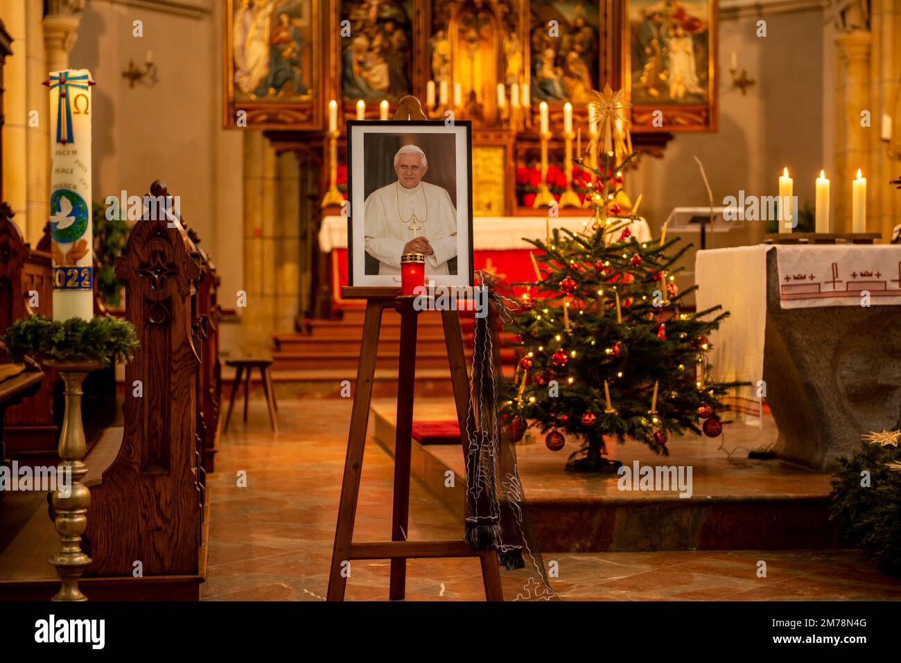 Portratl des verstorbenen Papstes Emeritus Benedikt XVI. In einer Kirche mit einem weihnachtsbaum und dem Altar im Hintergrund Stockfoto