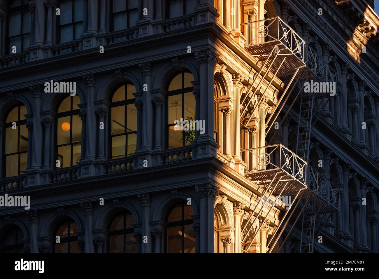 Die letzten Sonnenstrahlen auf den Lofthäusern in Soho mit Fassadenverzierungen und Feuerleiter. Soho Cast Iron Building Historic District, New York City Stockfoto