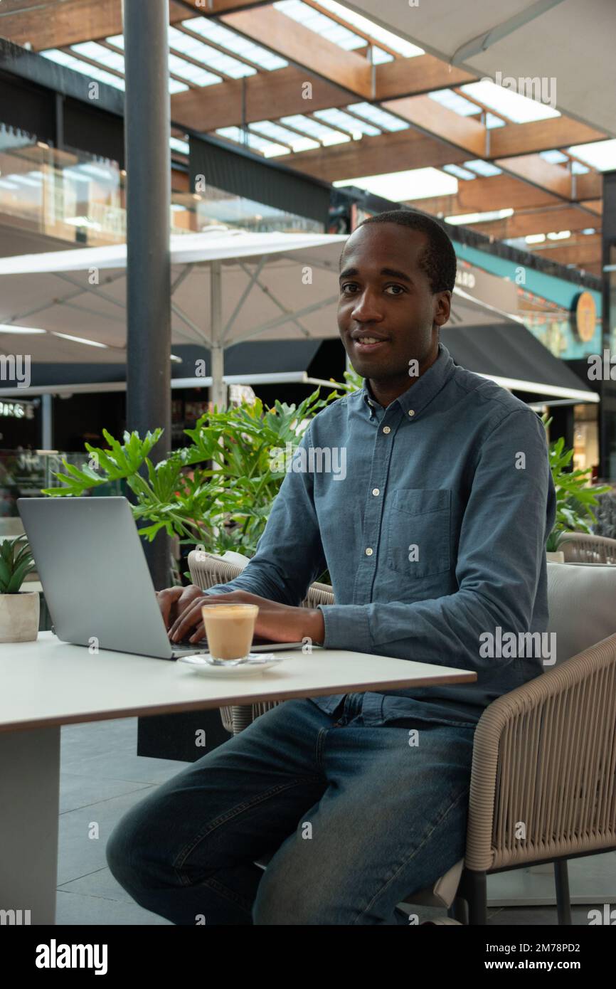 Ein junger afrikanischer Geschäftsmann mit seinem Laptop macht eine Kaffeepause Stockfoto