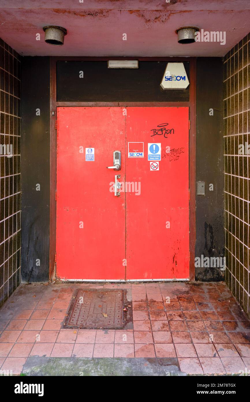 Rot lackierte Notausgang-Sicherheitstüren von außen mit Informationsaufklebern und Graffiti Stockfoto