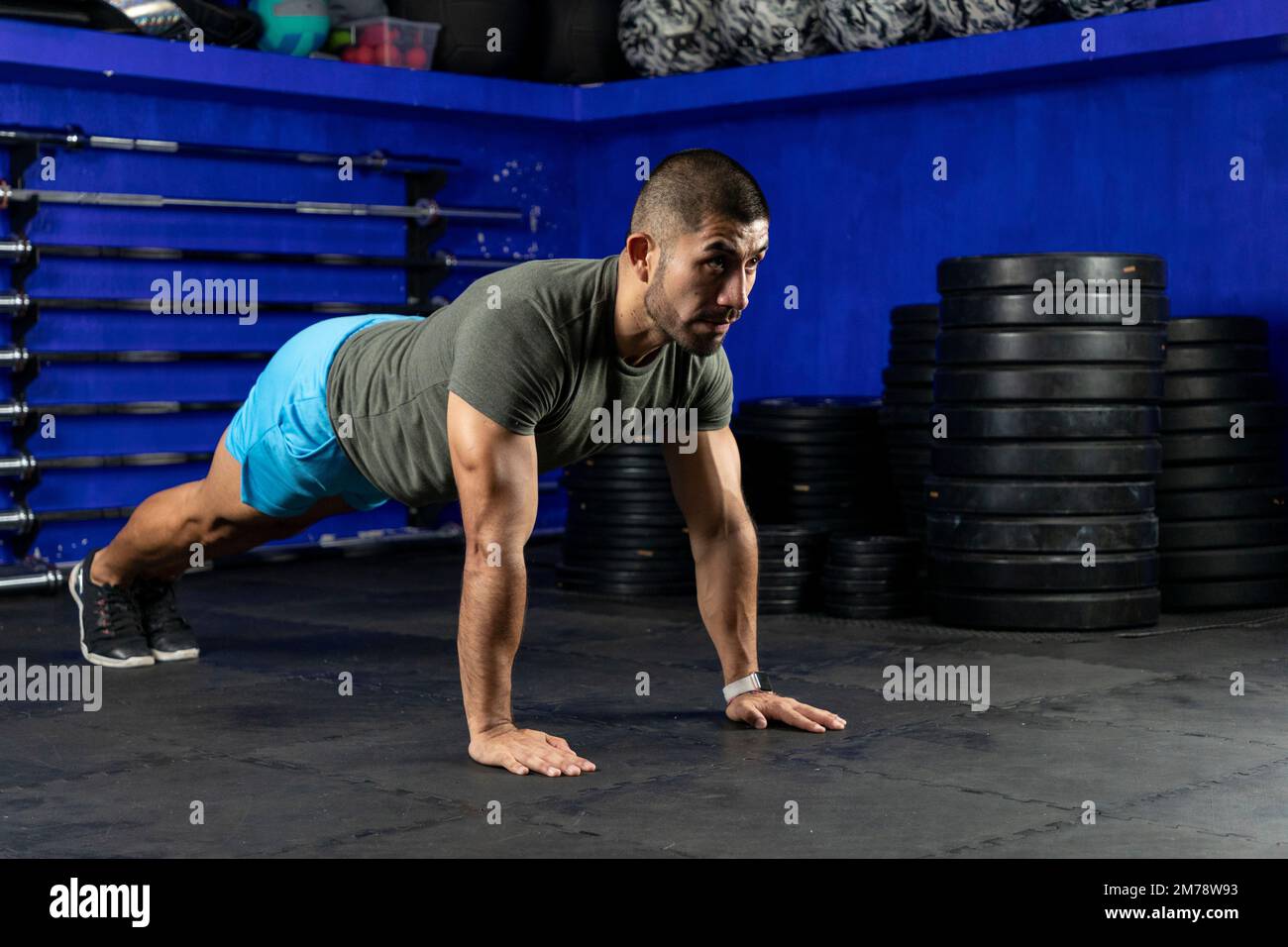 Ein Lateiner mit Sportbekleidung, der in einem Crossfit-Gym eine hohe Planke macht Stockfoto