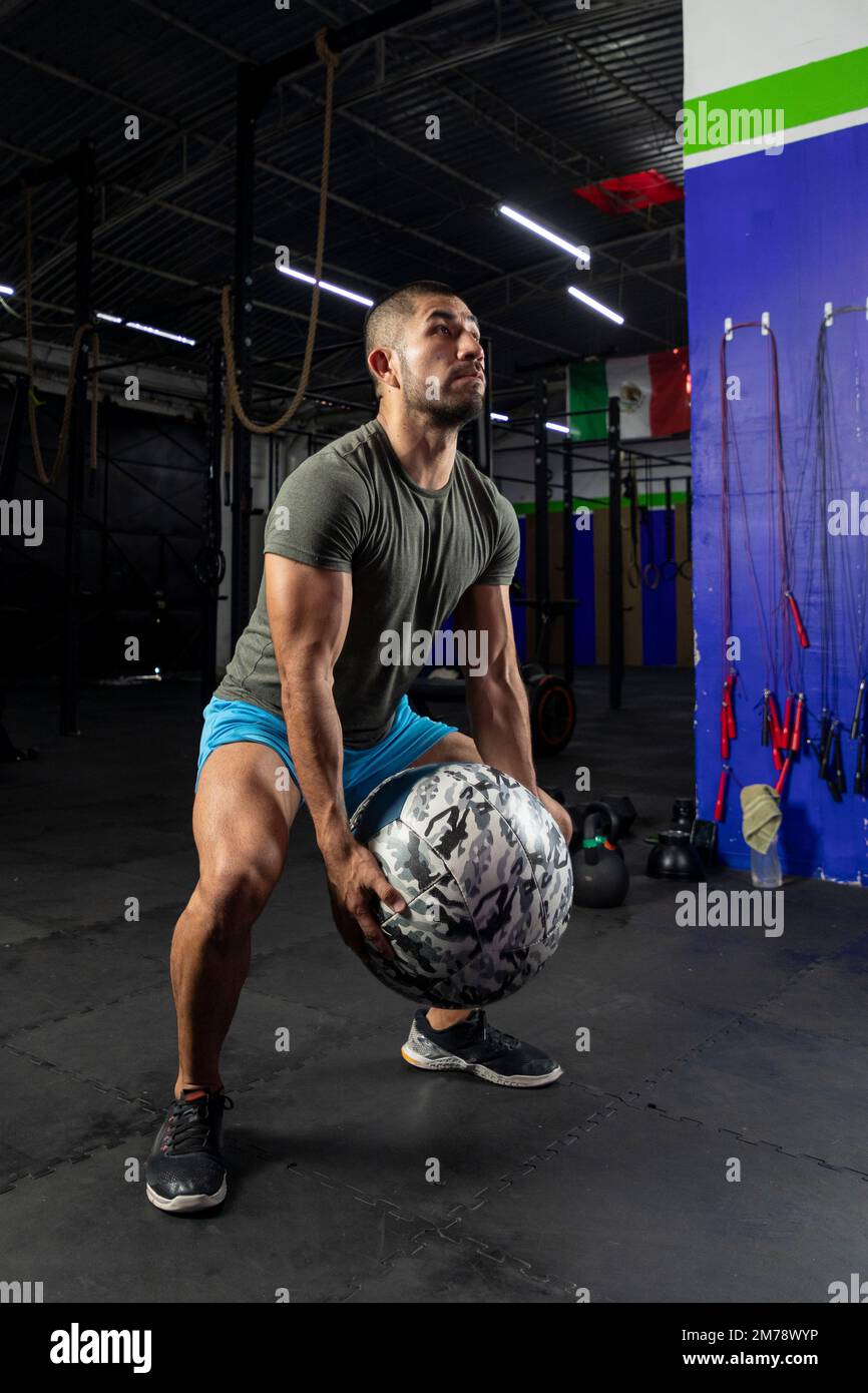 Mann in Sportbekleidung, der mit einem Crossfit-Medizinball trainiert, in einem Fitnessstudio Stockfoto