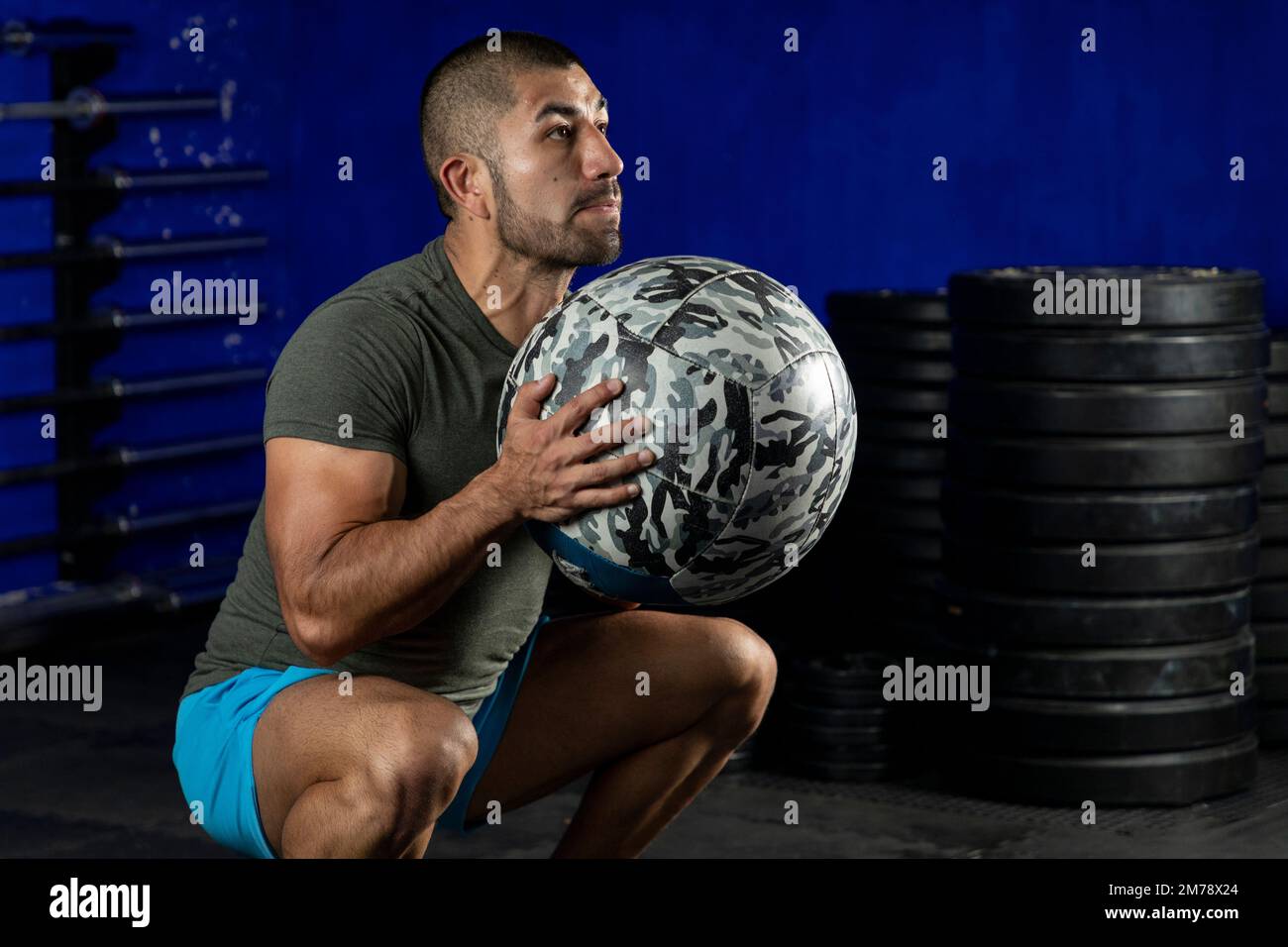 Ein lateinischer Mann, der im Fitnessstudio trainiert und einen Medizinball benutzt Stockfoto