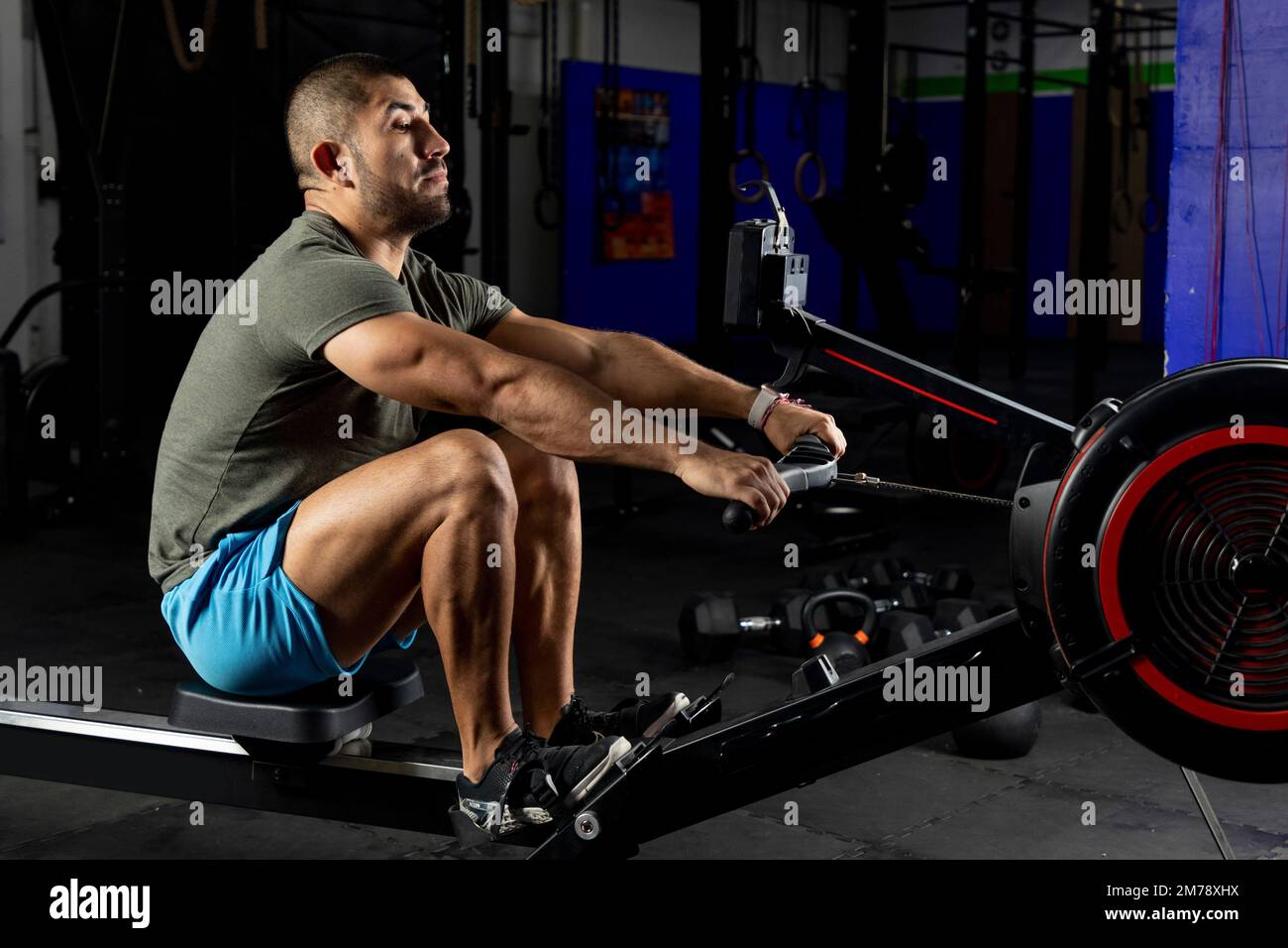 Ein Mann in Sportbekleidung rudert auf einer Maschine im Fitnessstudio Stockfoto