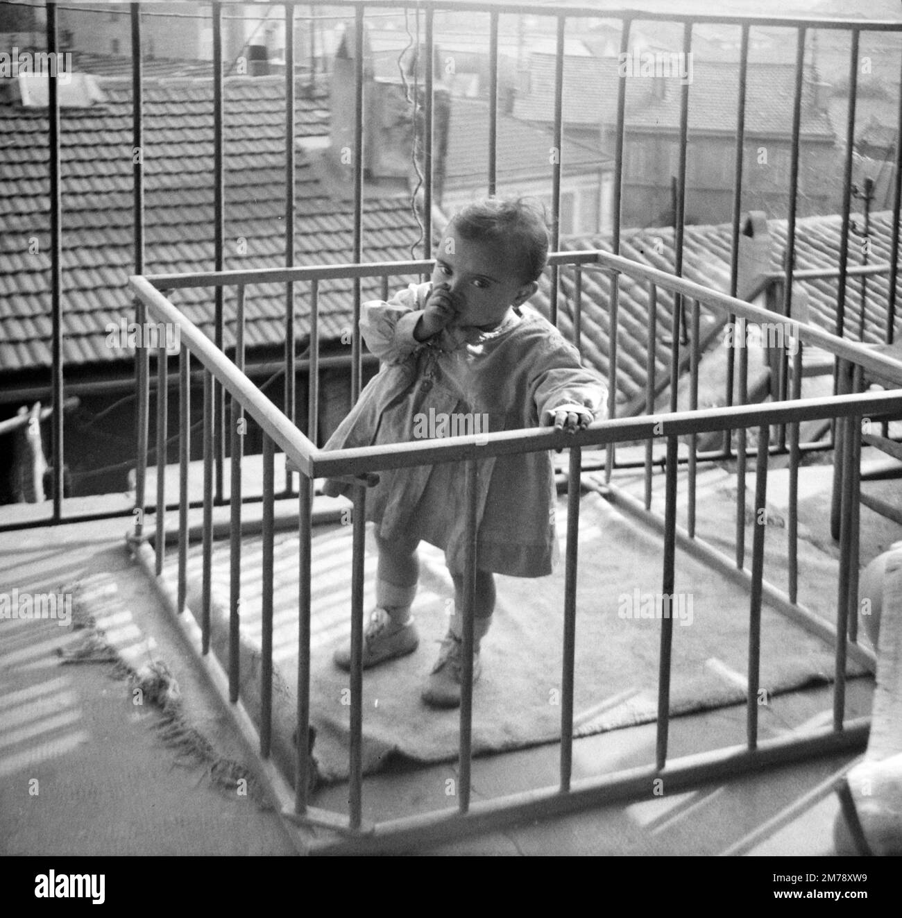Baby, Baby oder Kleinkind in einem hölzernen Kinderstall auf einem Balkon in Marseille, Frankreich 1945. Klassische Schwarzweiß- oder Schwarzweißfotos. Stockfoto