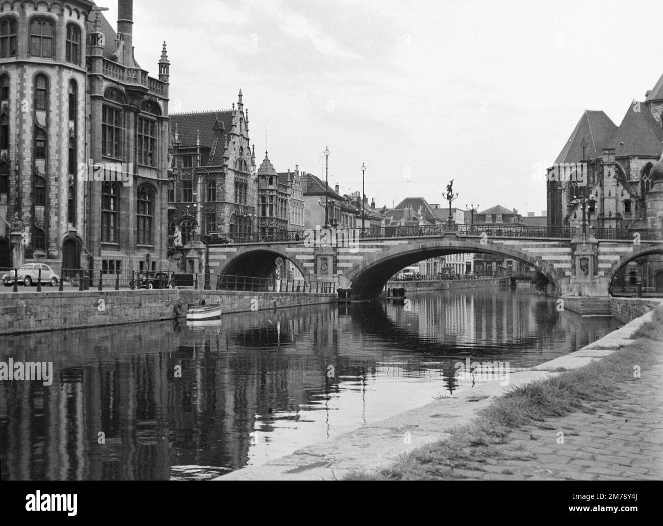 1960er Blick auf den Riverside Graslei Quay am Leie River und die mittelalterliche St. Michael's Bridge in der Altstadt oder dem historischen Viertel Gent Belgien c1960. Klassische Schwarzweiß- oder Schwarzweißfotos. Stockfoto