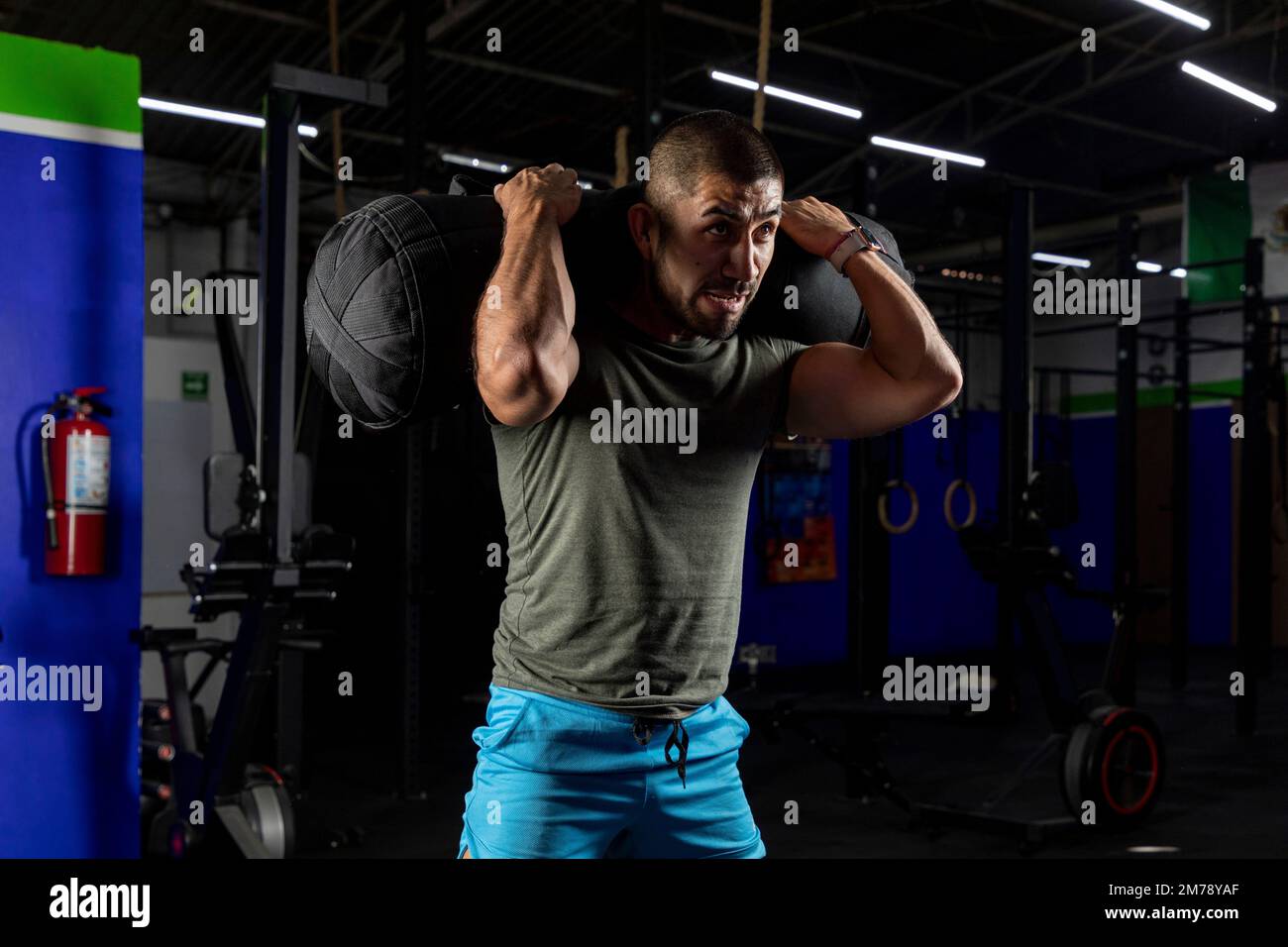 Nahaufnahme eines Mannes in Sportbekleidung in einem Fitnessstudio, der Squats mit einem Sandsack auf dem Rücken macht Stockfoto