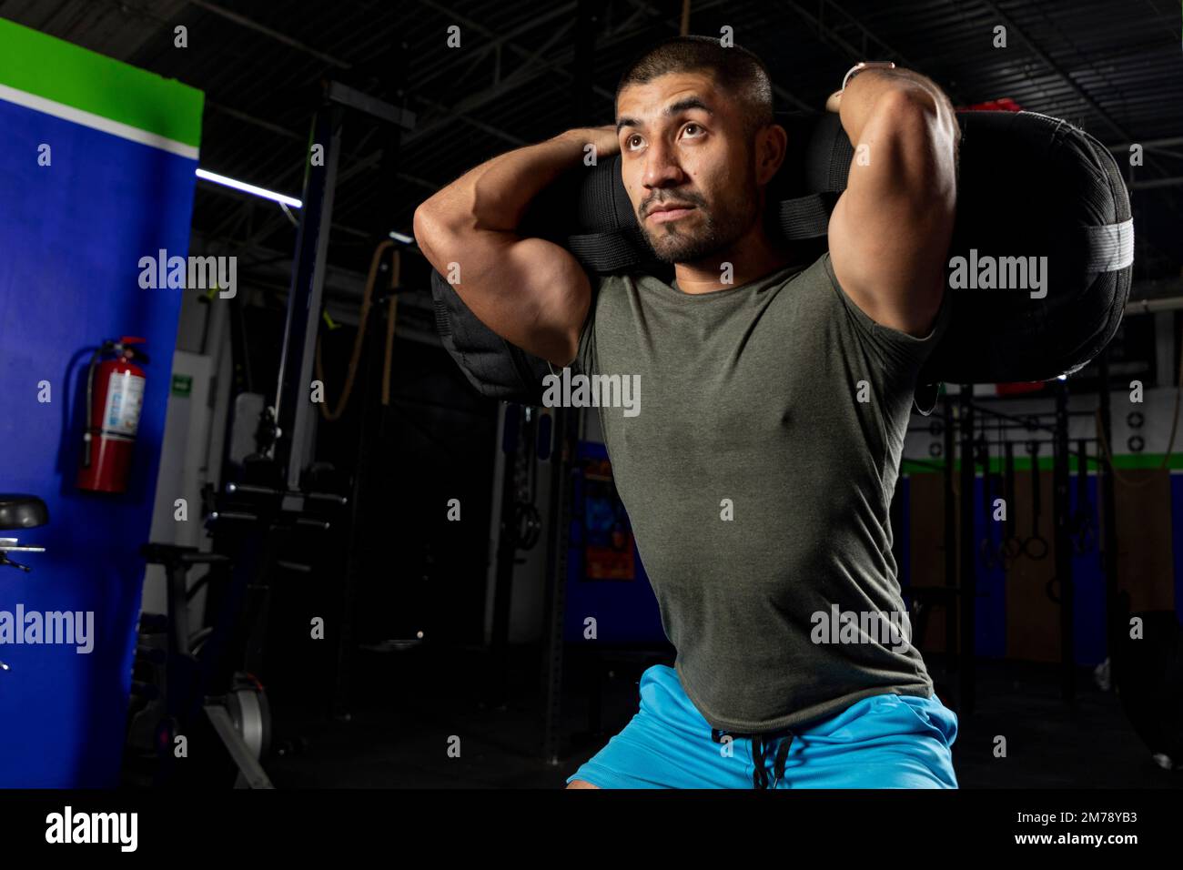 Nahaufnahme eines Mannes in Sportbekleidung in einem Fitnessstudio, der Squats mit einem Sandsack auf dem Rücken macht Stockfoto
