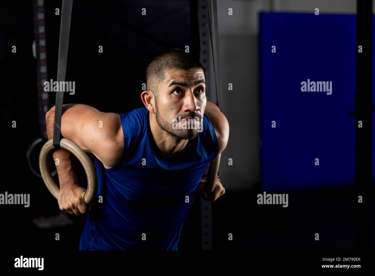 Ein Latino in Sportbekleidung, der Gymnastikübungen an einigen Ringen in einem Fitnessraum macht Stockfoto