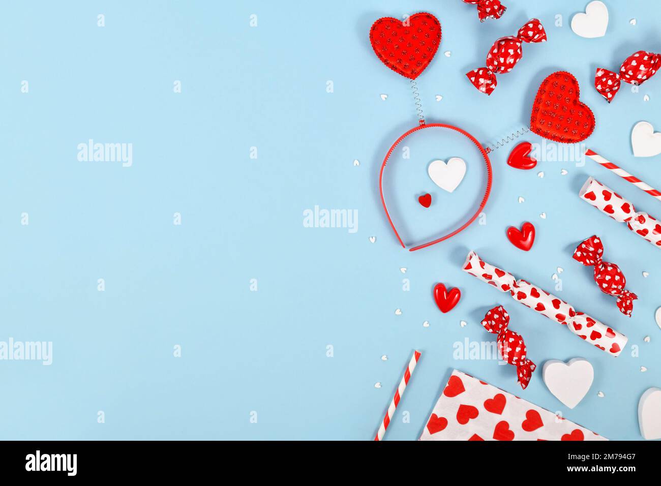 Niedliches flaches Laken zum Valentinstag mit Herzverzierungen, Stirnband und Süßigkeiten auf blauem Hintergrund mit Kopierbereich Stockfoto
