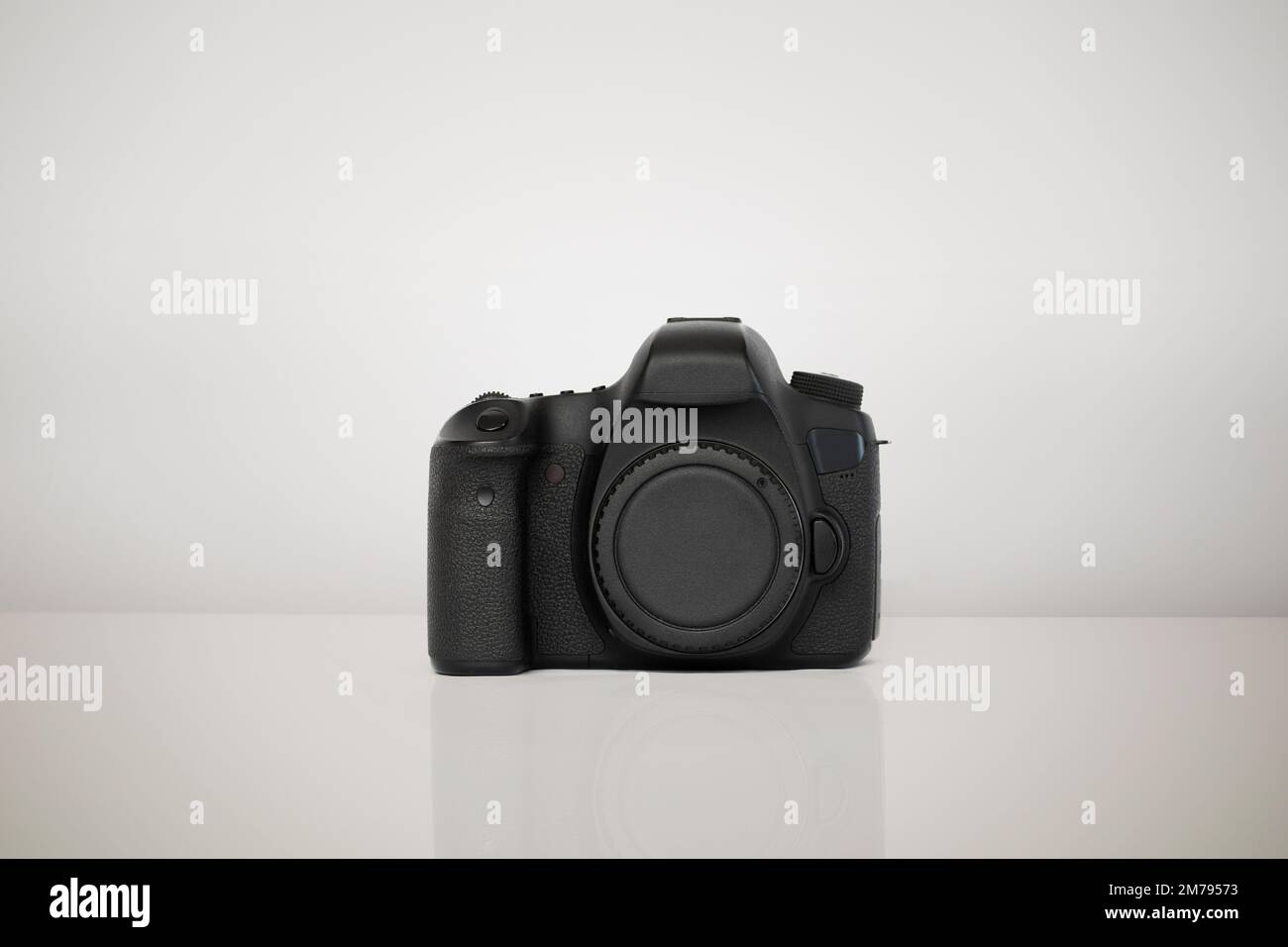 Kamera isoliert auf weißem Hintergrund. Die Kamera wird auf einer glänzenden Oberfläche platziert, die die Form der Kamera widerspiegelt Stockfoto