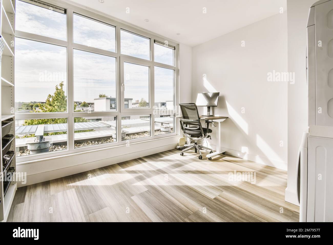 Ein Zimmer mit Holzfußboden und großen Fenstern, die auf die Stadtlandschaft blicken Stockfoto