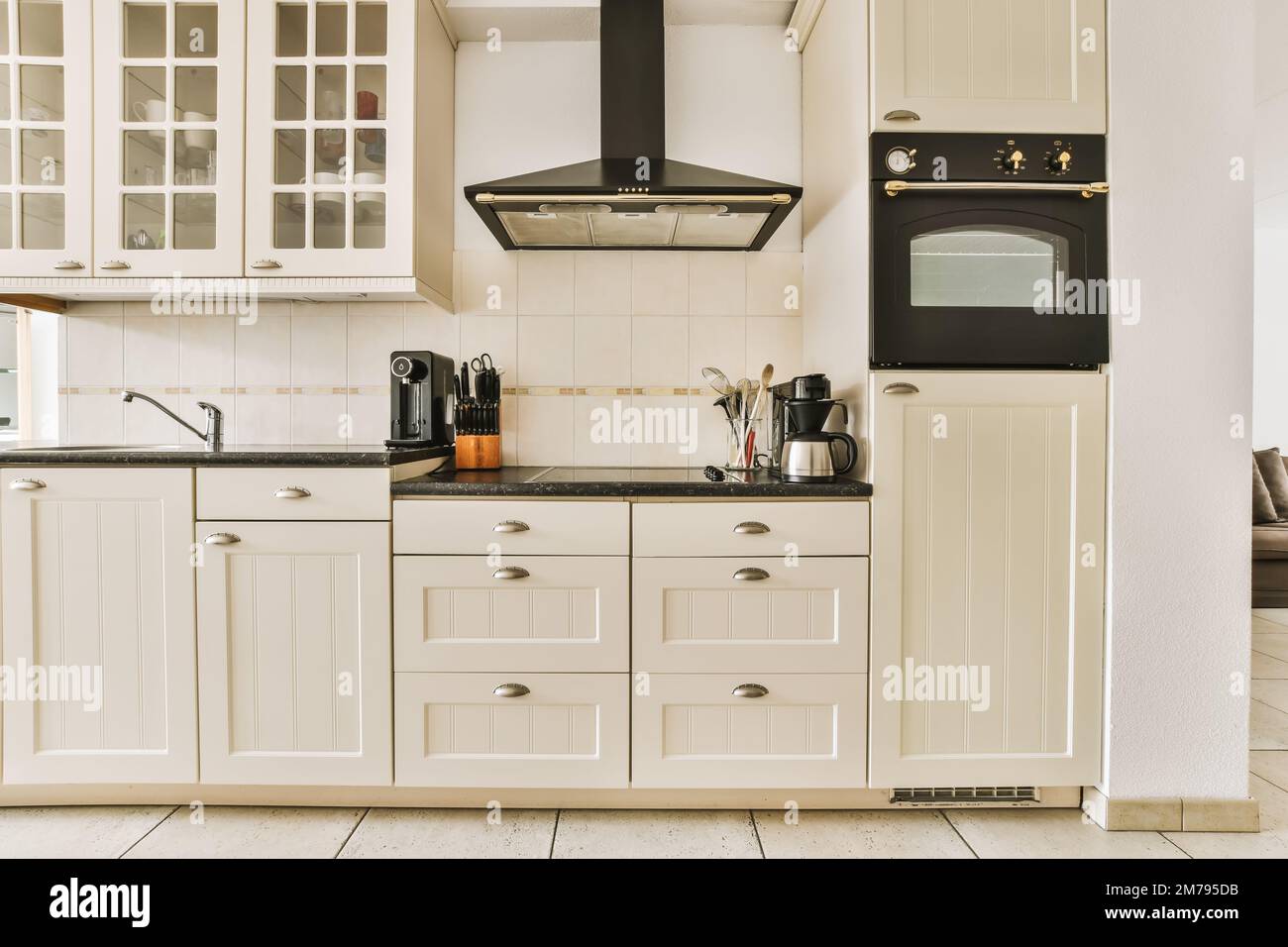Eine Küche mit weißen Schränken und schwarzen Ablageflächen auf den Ablagen auf diesem Foto wird von innen aufgenommen Stockfoto