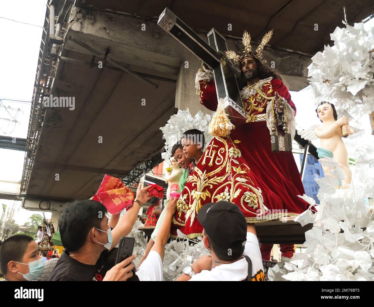 Kinder, die Nazarener Taschentücher von Gläubigen bekommen, um sie zur Nachbildung des Schwarzen Nazarenen zu wischen. Katholische Anhänger strömen in die Quiapo Kirche in Manila, um ihre Hingabe zum Schwarzen Nazarener auszudrücken, ein lebensgroßes Bild von dunkel gehäutetem, knienden Jesus Christus mit dem Kreuz. Einen Tag vor dem Festmahl am 9. Januar. Diese festliche Aktivität wurde wegen der COVID-19-Pandemie für zwei Jahre ausgesetzt. Stockfoto