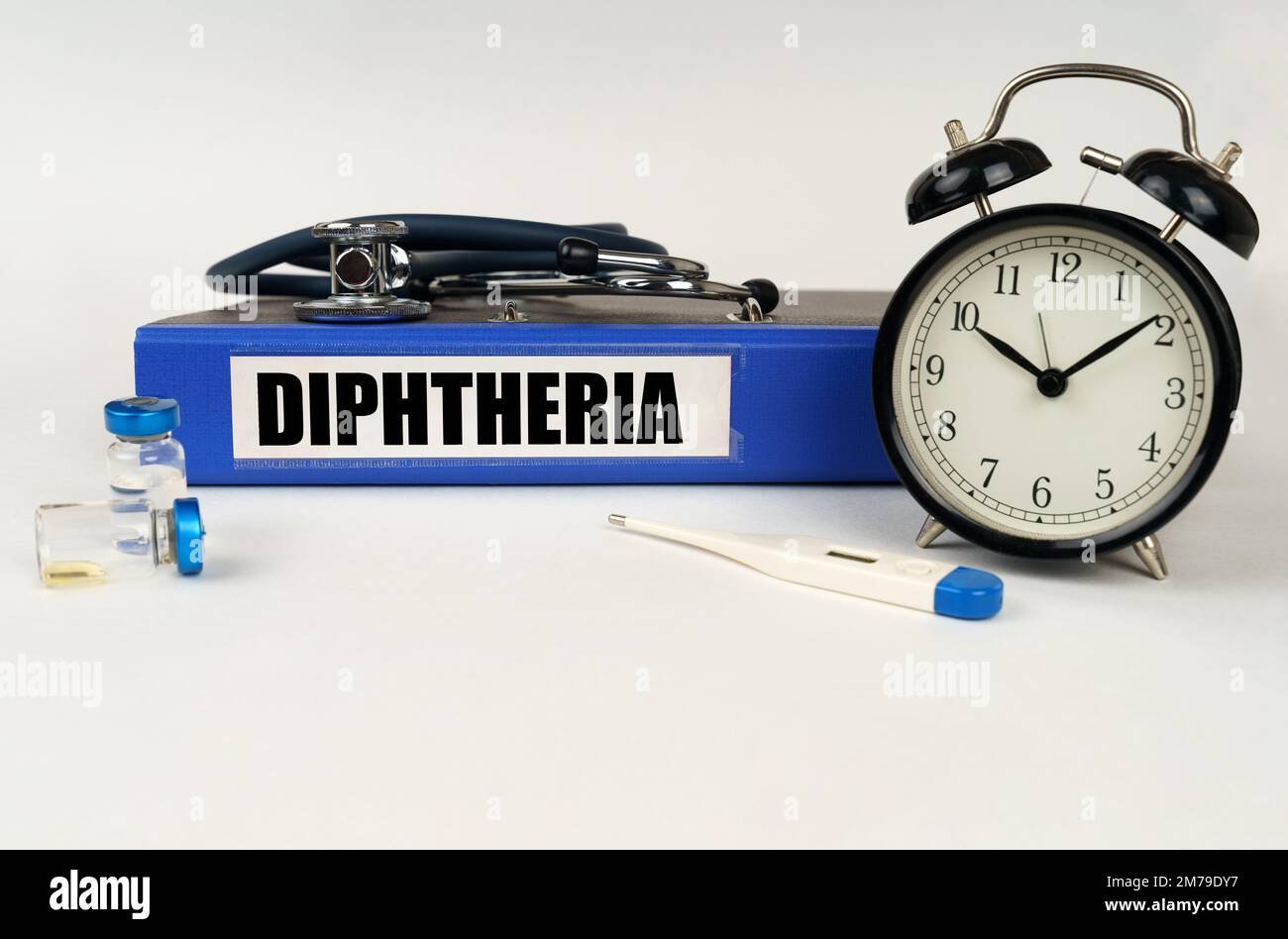 Medizinisches Konzept. Auf einer weißen Oberfläche, einem Thermometer, Ampullen, einem Stethoskop, einem Wecker und einem Ordner mit der Aufschrift Diphtherie Stockfoto