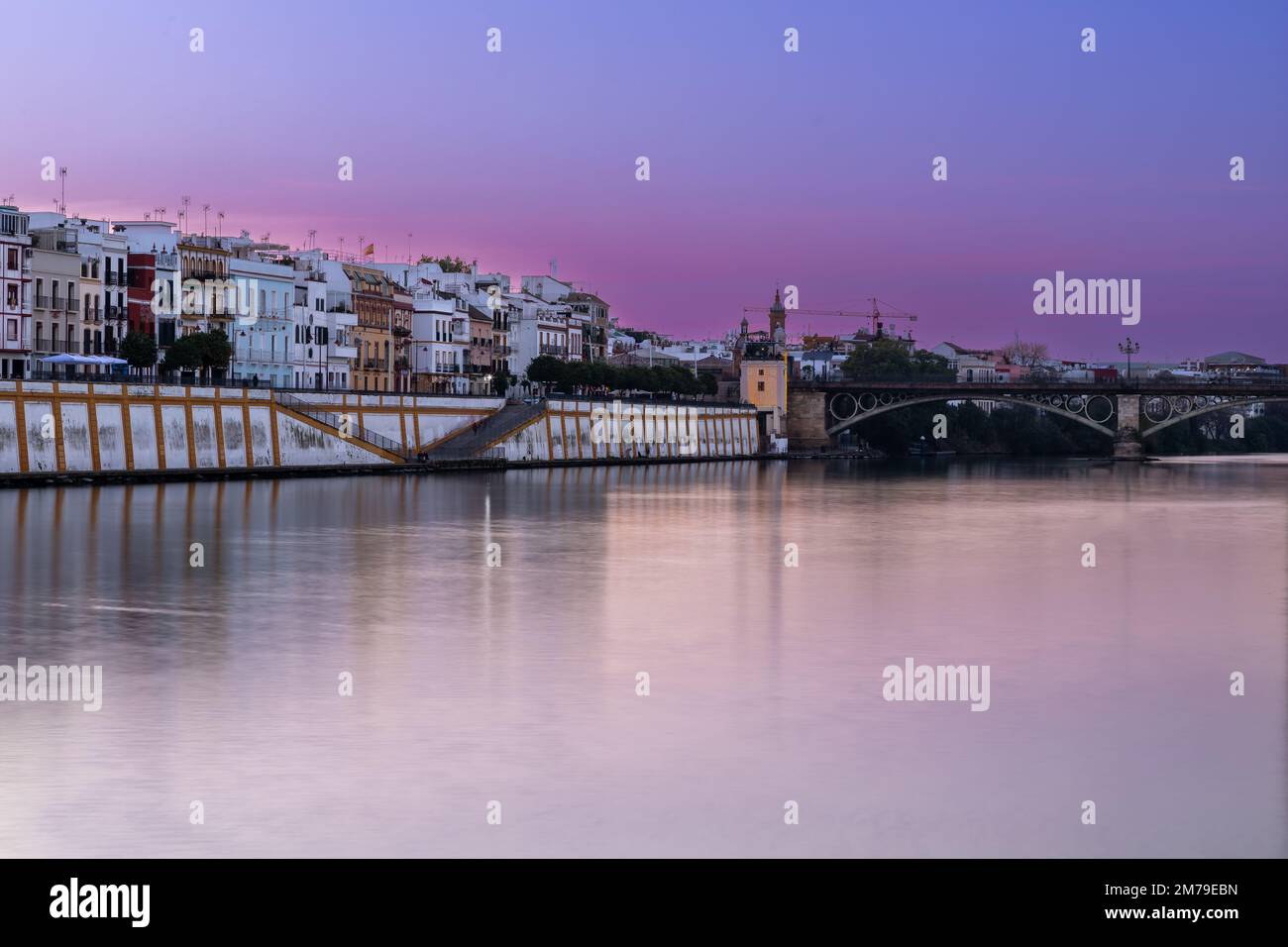 Sonnenuntergang über dem authentischen Viertel Tirana in Sevilla mit Blick auf Calle Betis, Torre Sevilla und mit überwältigenden Reflexionen im Guadalquivir Stockfoto