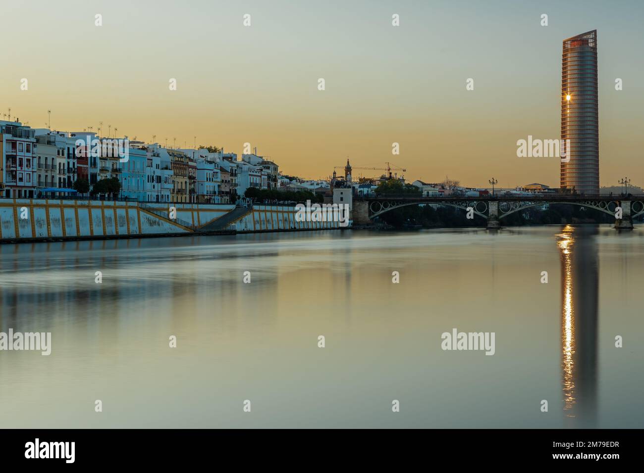 Sonnenuntergang über dem authentischen Viertel Tirana in Sevilla mit Blick auf Calle Betis, Torre Sevilla und mit überwältigenden Reflexionen im Guadalquivir Stockfoto