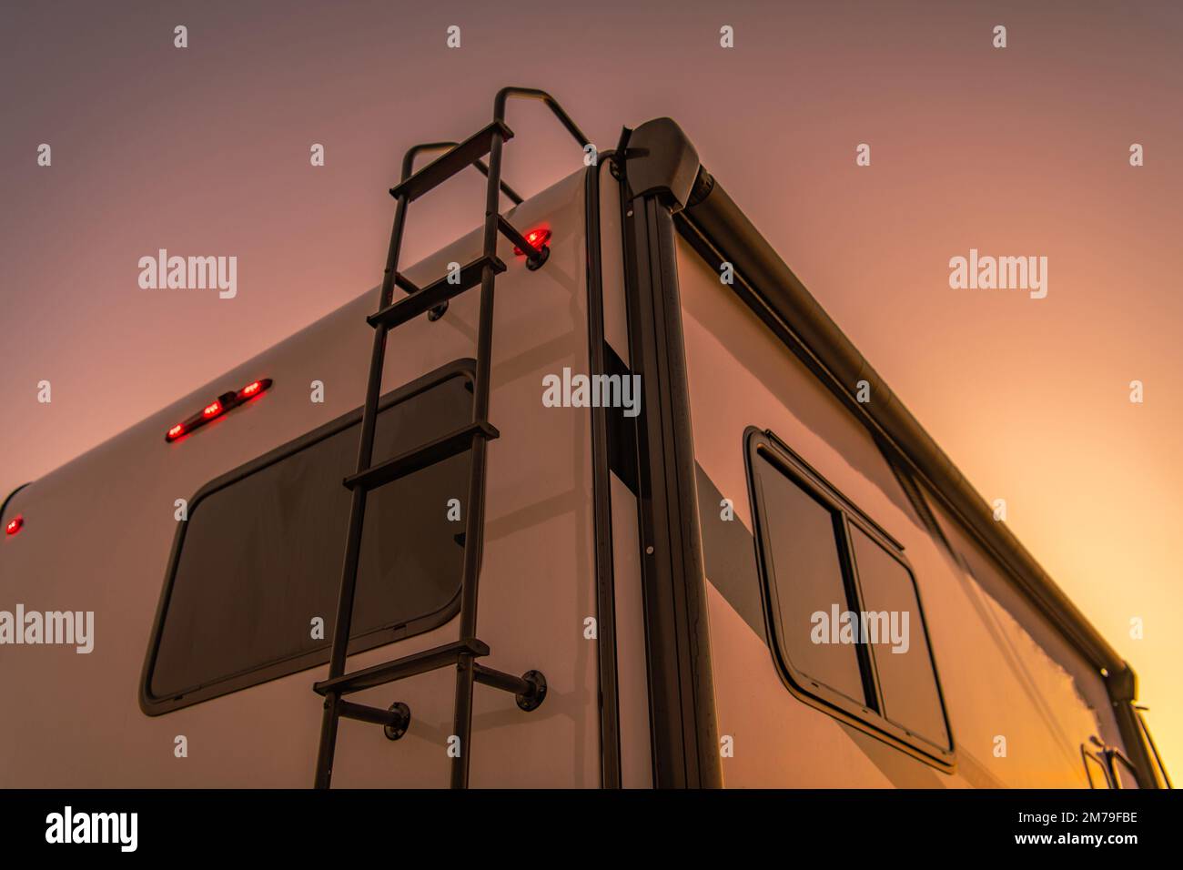 Nahaufnahme eines hinteren Teils des modernen Wohnmobils mit Stufen zum  Dach im Licht der untergehenden Sonne. Motto „Motorheim Reisen“  Stockfotografie - Alamy