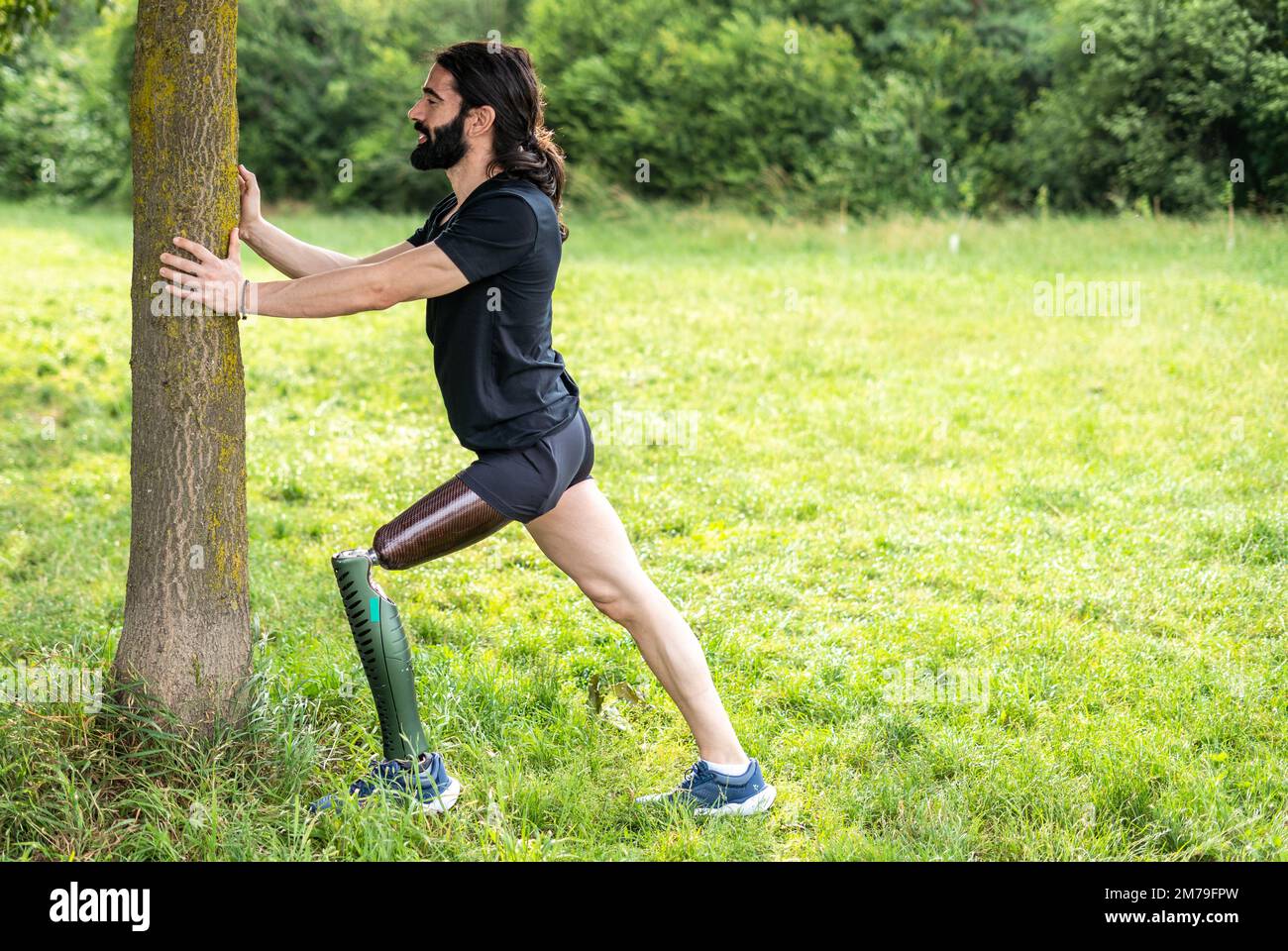 Ein behinderter Sportler mit amputiertem Bein beginnt mit dem Stretching, bevor er im Park im Freien läuft Stockfoto