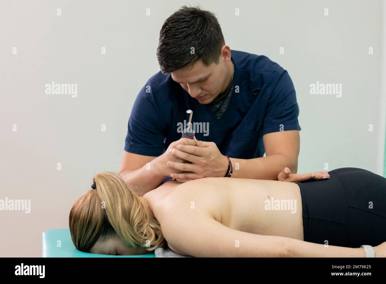 Physiotherapeut behandelt die Fibrolyse seines Patienten mit einem Haken und massiert seinen Rücken Stockfoto